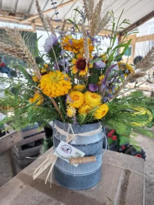 Composition très champêtre dans un pot à lait en zinc avec zinnias jaunes, blé et lavande, ferme florale Morbihan