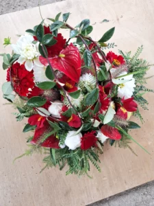 Élégante composition florale ronde avec anthurium rouge, dahlias de saison et lianes retombantes, créée à la ferme à Languidic
